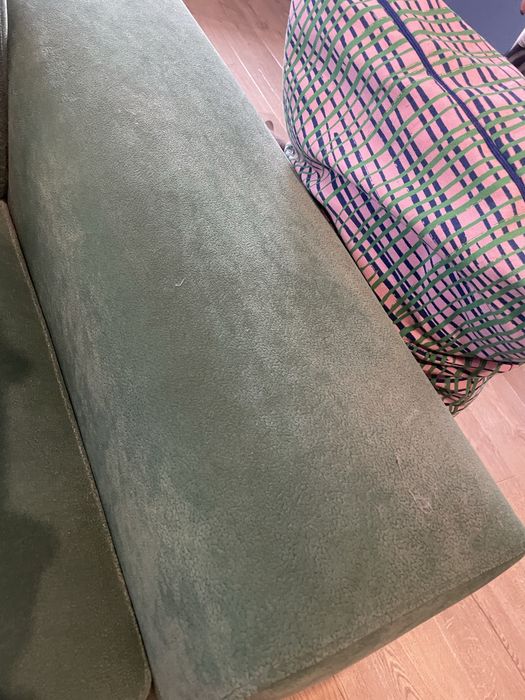 Zielona butelkowa sofa z funkcja spania z pufami i drewnianymi półkami