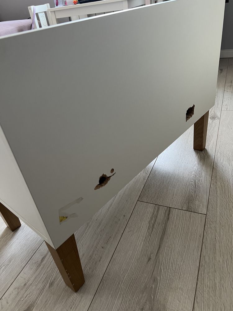 Mała biala szafka na nożkach w stylu skandynawskim.