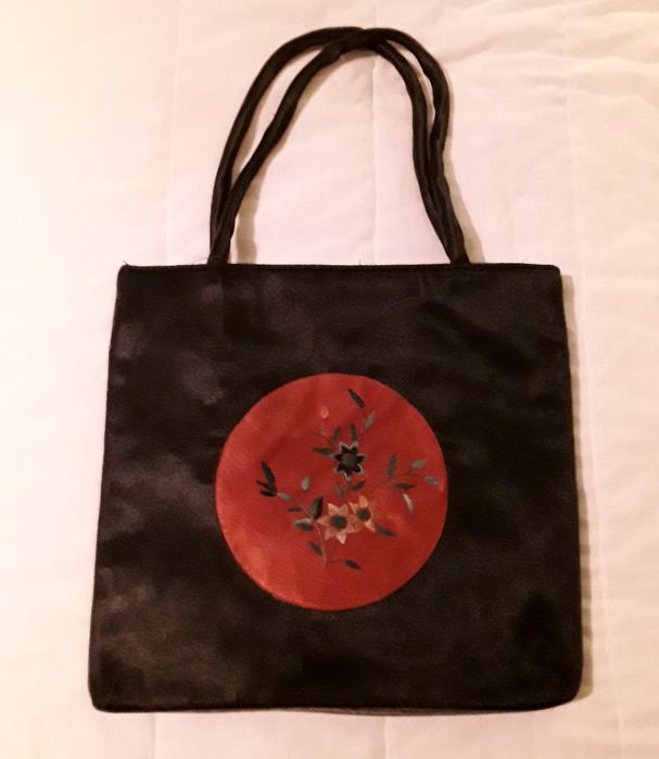 Bolsa ou mala de mão preta com aplicação circular vermelha
