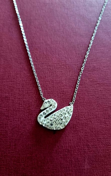 Colar prateado, em aço, com pingente em forma de cisne branco.