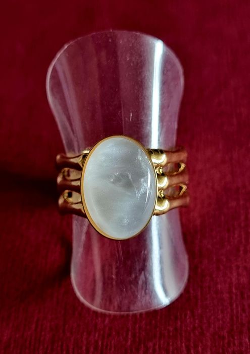 Anel dourado, em aço, com uma madrepérola oval.  Ajustável