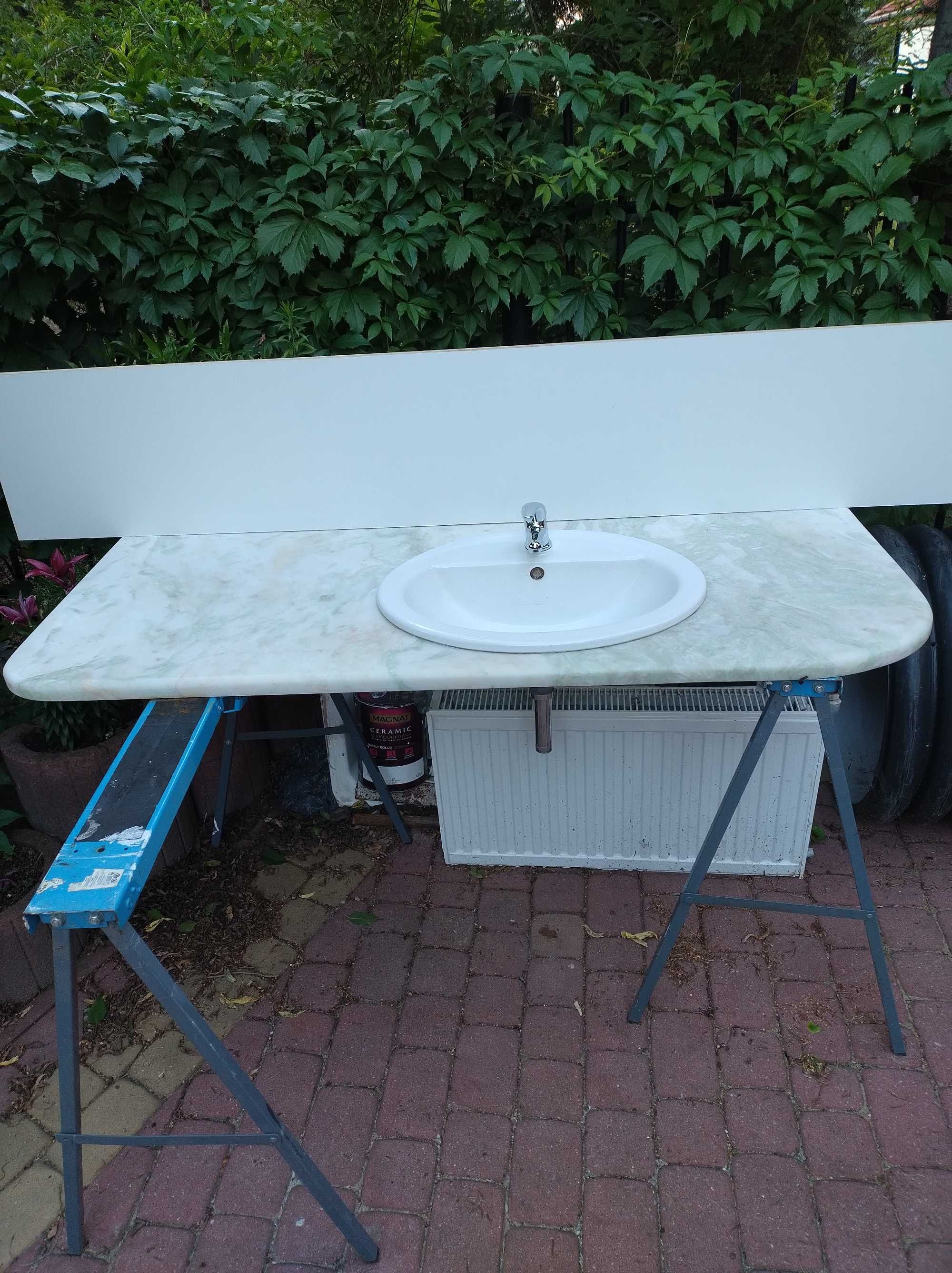 Blat łazienkowy z kamienia z umywalką i lustrem.