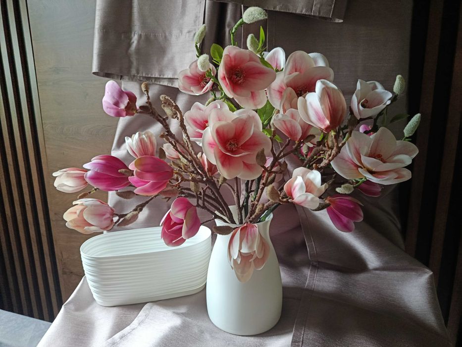 Zasłony beżowe, wazon szklany z magnolią, doniczka biała