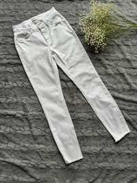 Białe spodnie jeansy rurki z regularnym stanem szarpane nogawki