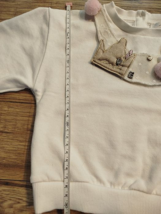 Biała bluza bawełna 80 86 z ozdobną odpinaną dekoracja na dekolcie.