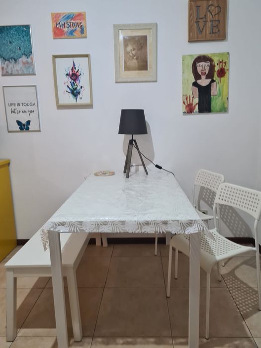Mesa de jantar com 4 cadeiras e banco corrido em branco.