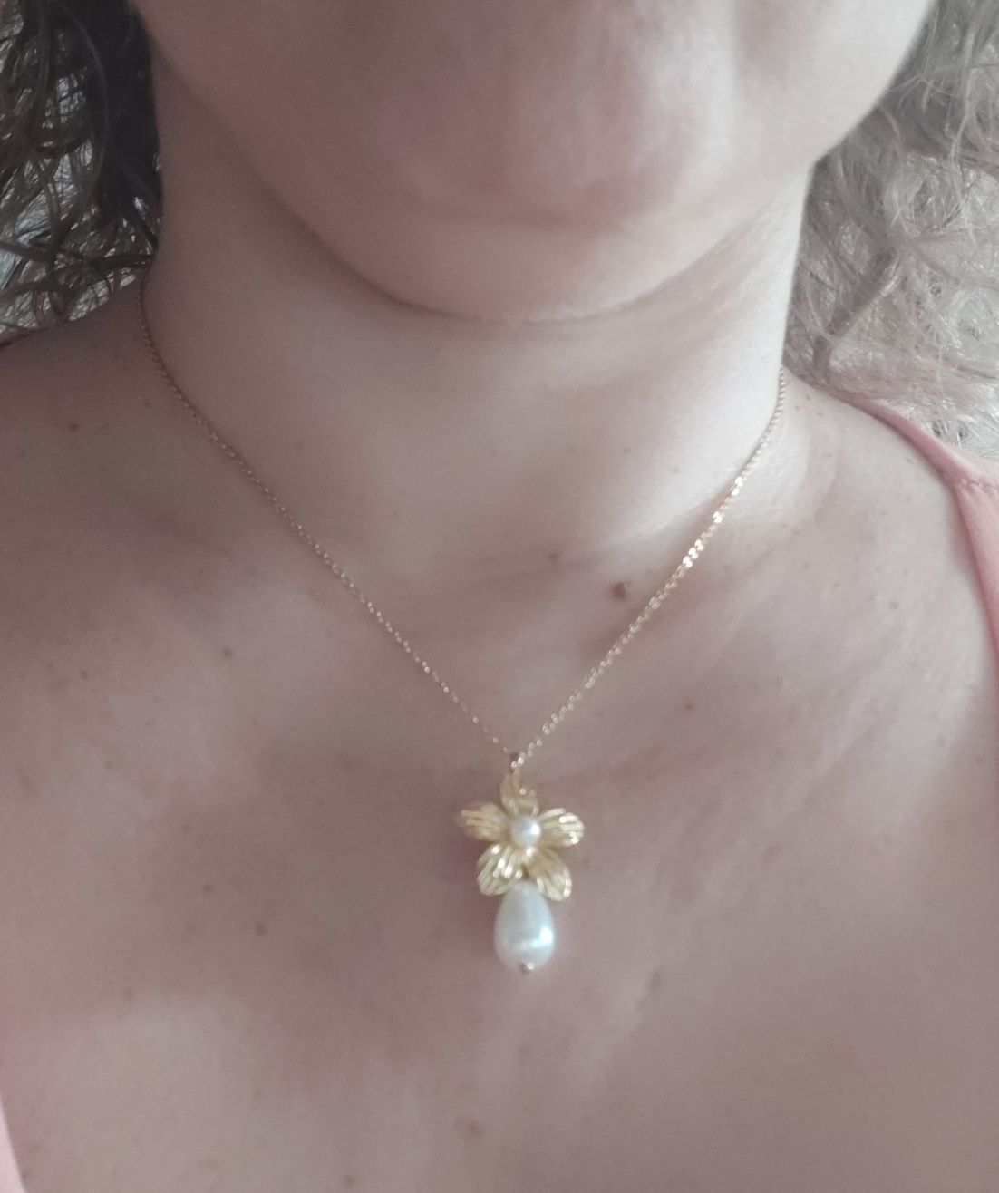 Colar dourado, em aço, com flor e pérolas. Tem extensor