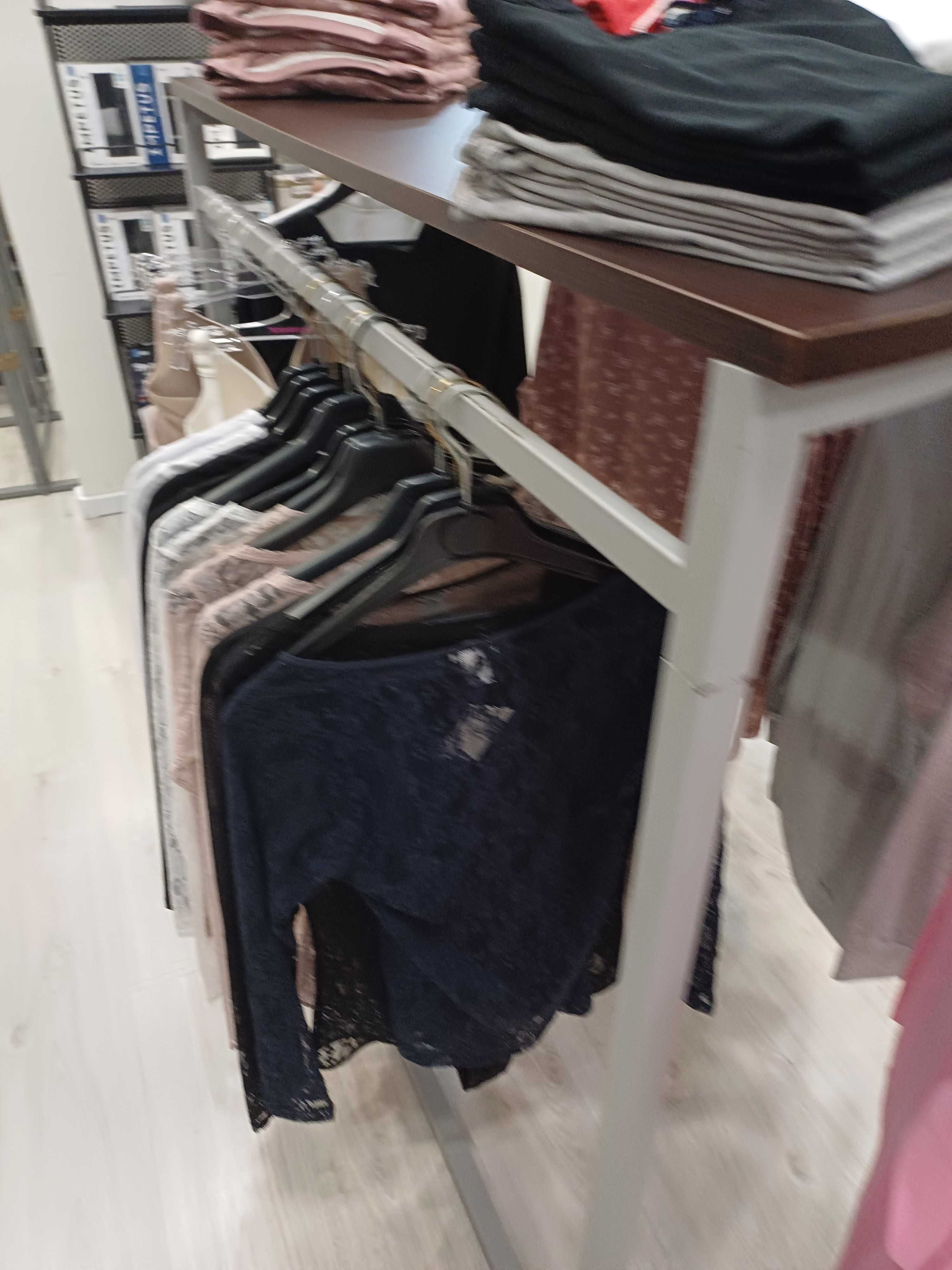 Expositor de roupa cinza com tampo em wengue, em formato de meia lua.