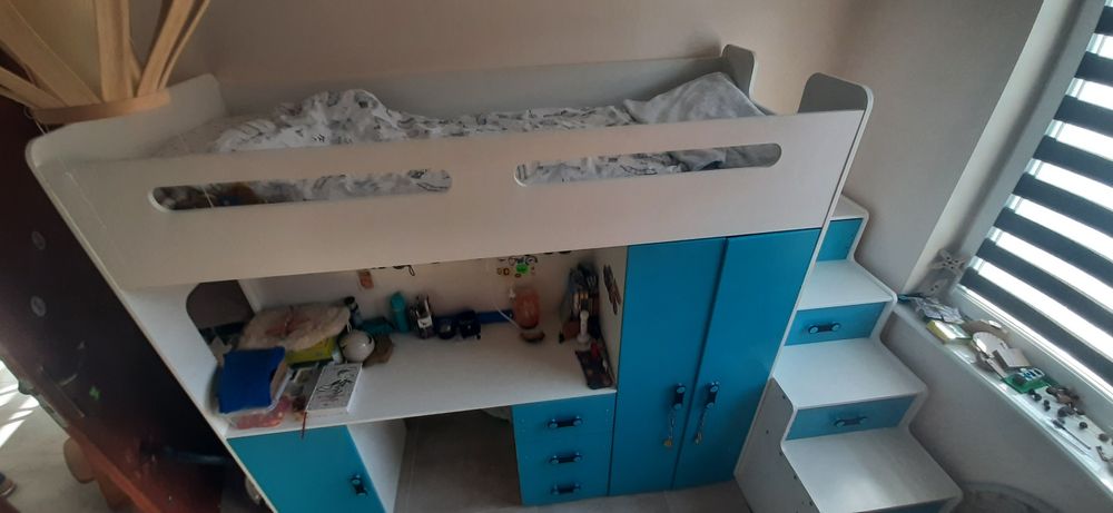 Łóżko piętrowe z biurkiem i schodami.