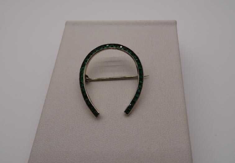 Antyczna srebrna broszka podkowa zielone szmaragdowe kamienie.