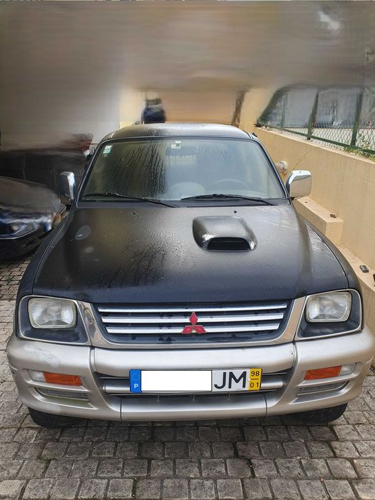 Mitsubishi L200 preta e prateada com engate de reboque