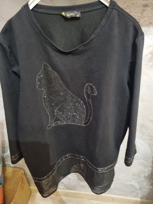 Śliczna czarna bluzka ozdobiona aplikacją w kształcie kota z cekinów.