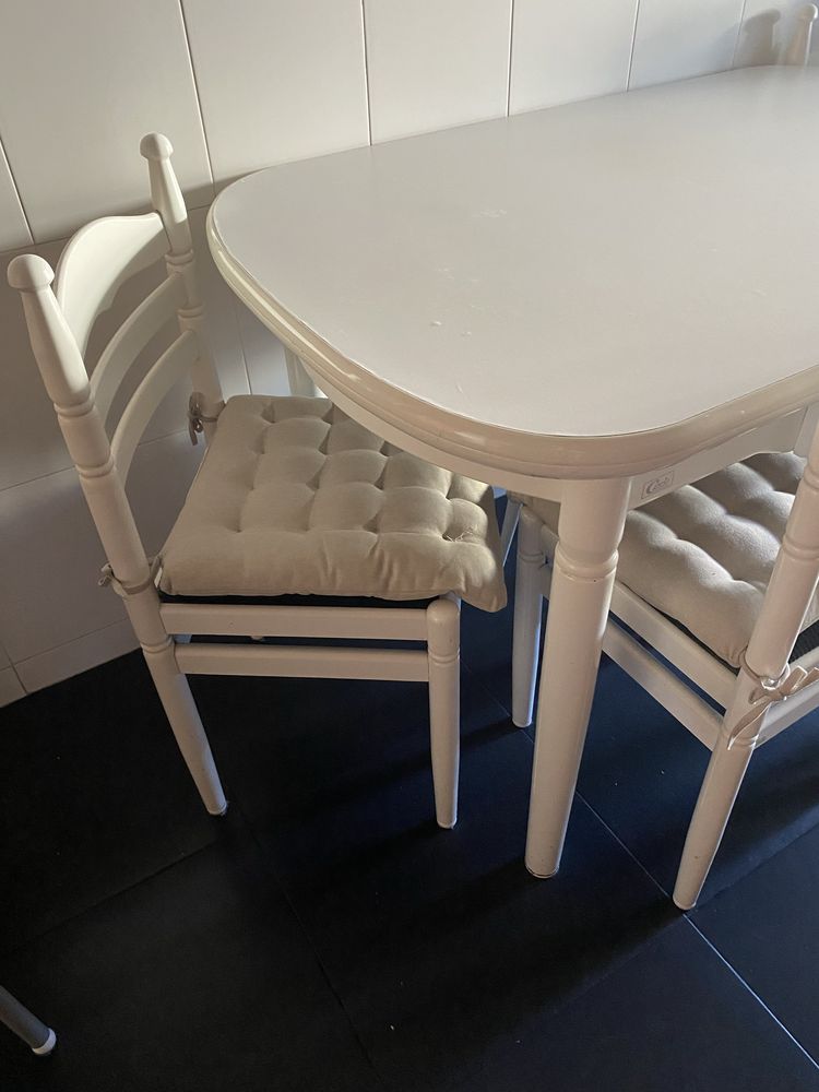 Mesa com 4 cadeiras e um banco lacada de branco com cuchins