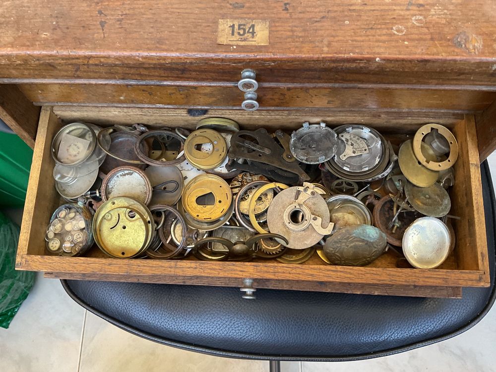 Pequeno armário com centenas de peças de relógios de bolso