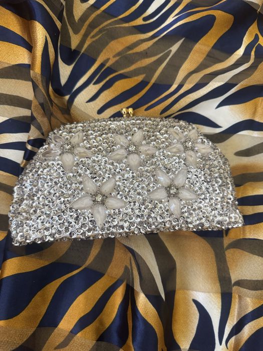 Mala com micangas prateadas e fores compoe o conjunto