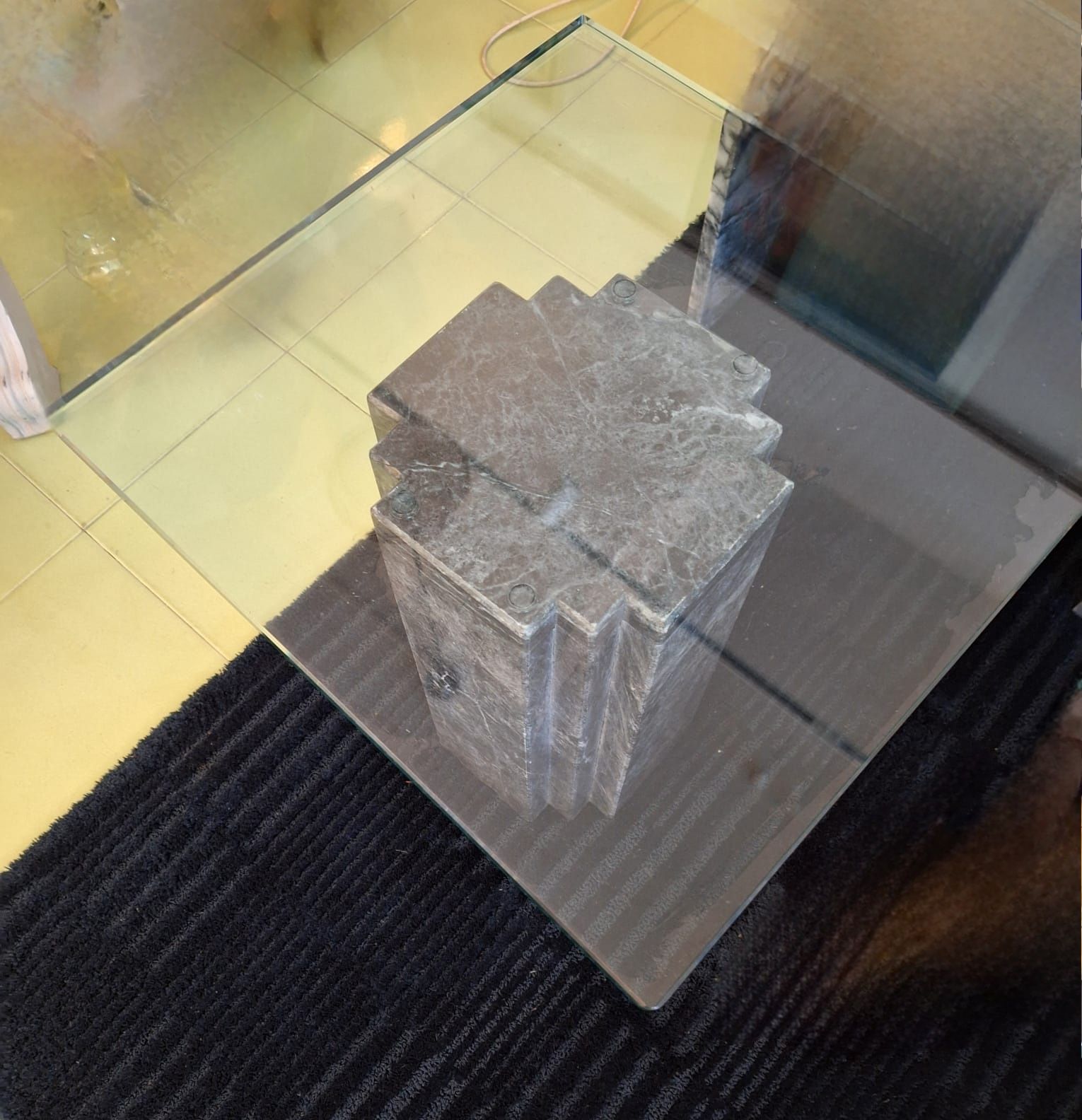 Mesa com apoio de mármore negro maciço e tampo em vidro.