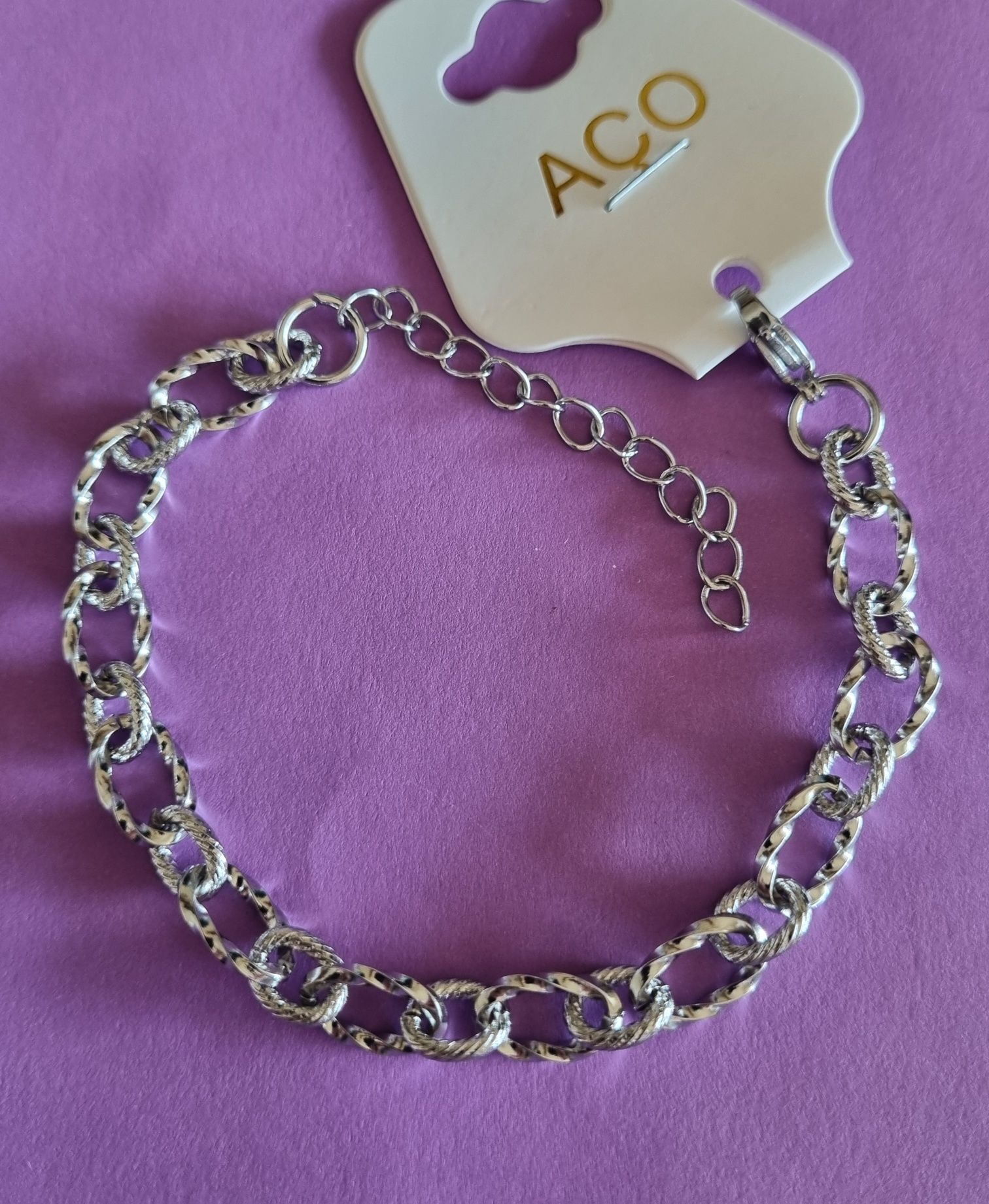 Pulseira prateada, em aço, com elos trabalhados. Tem extensor