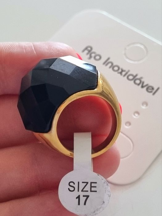 Anel dourado, em aço, com grande pedra preta facetada. T17