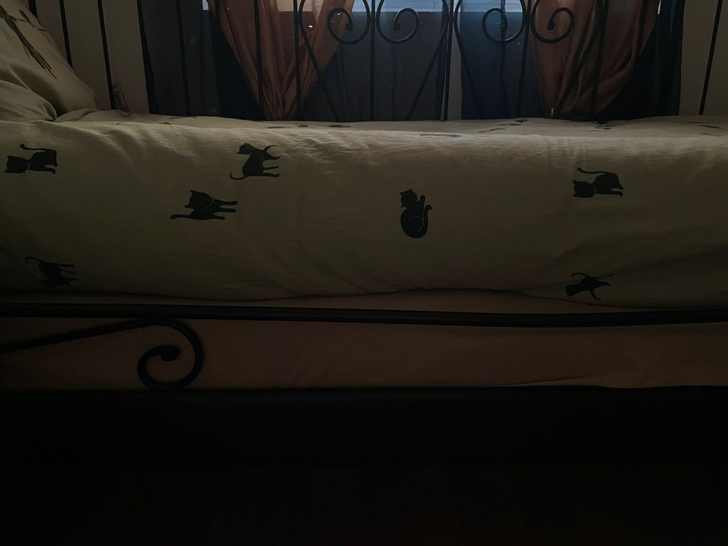 Cama de ferro preta com colchões e mesa de cabeceira
