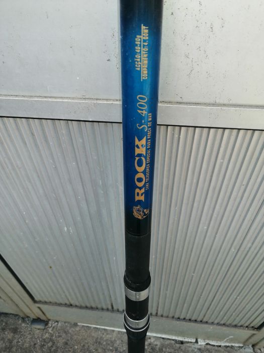 Uma cana de pesca usada pronta a usar e um carreto estão adicional