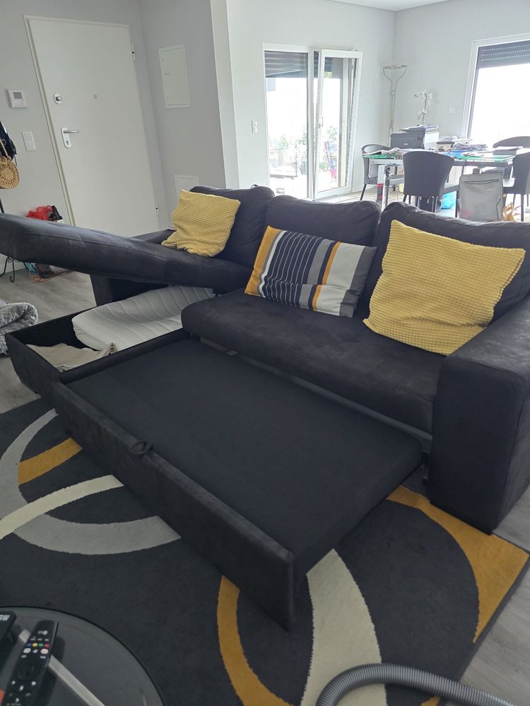 Sofa cinza escuro com arrumos e cama