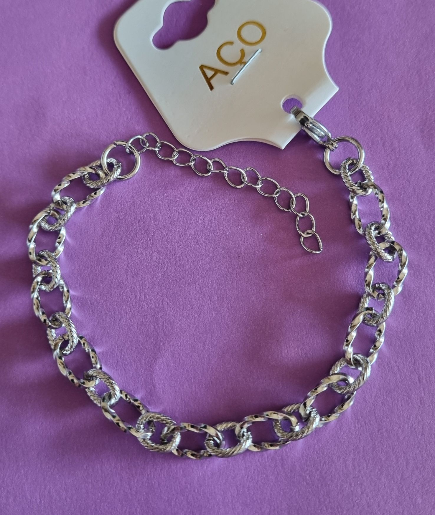 Pulseira prateada, em aço, com elos trabalhados. Tem extensor