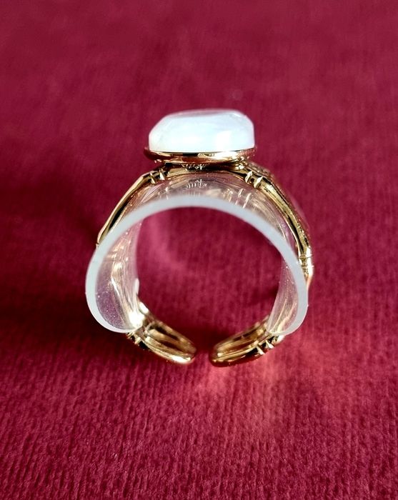 Anel dourado, em aço, com uma madrepérola oval.  Ajustável