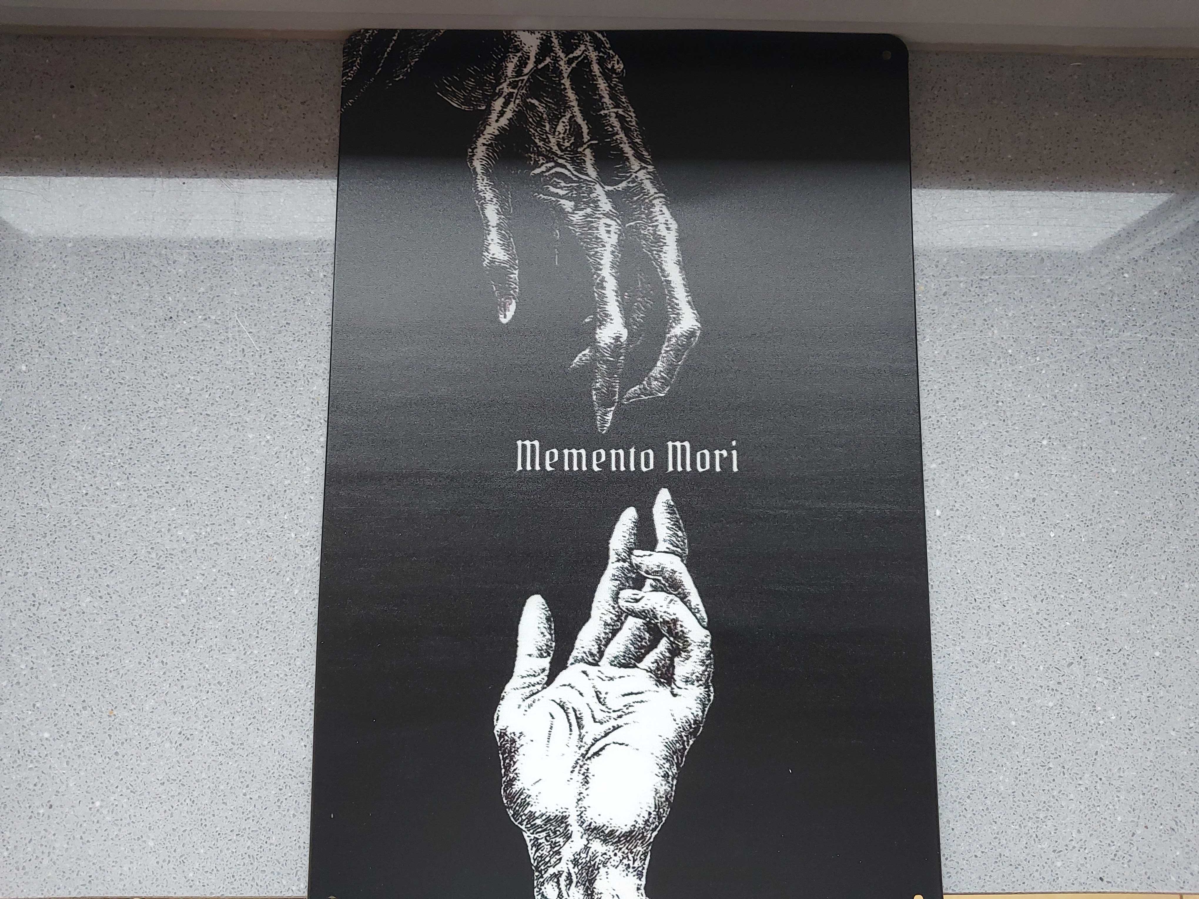 Metalowa tablica z napisem Memento Mori.