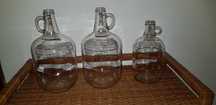 Garrafões de vidro com pega "ONE GALLON" e "ONE HALF GALLON"