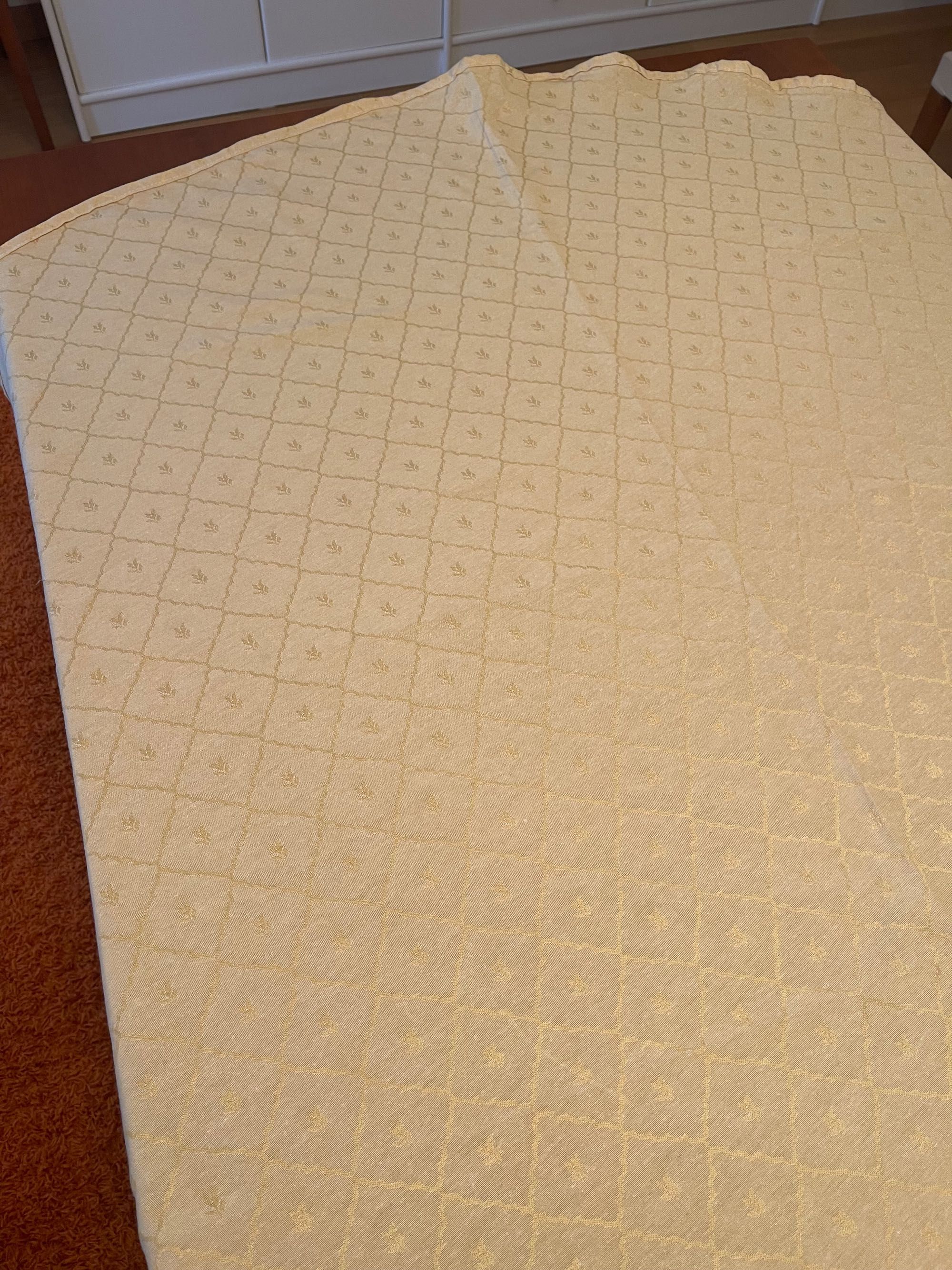 Toalha de mesa redonda em tom creme com detalhes dourados