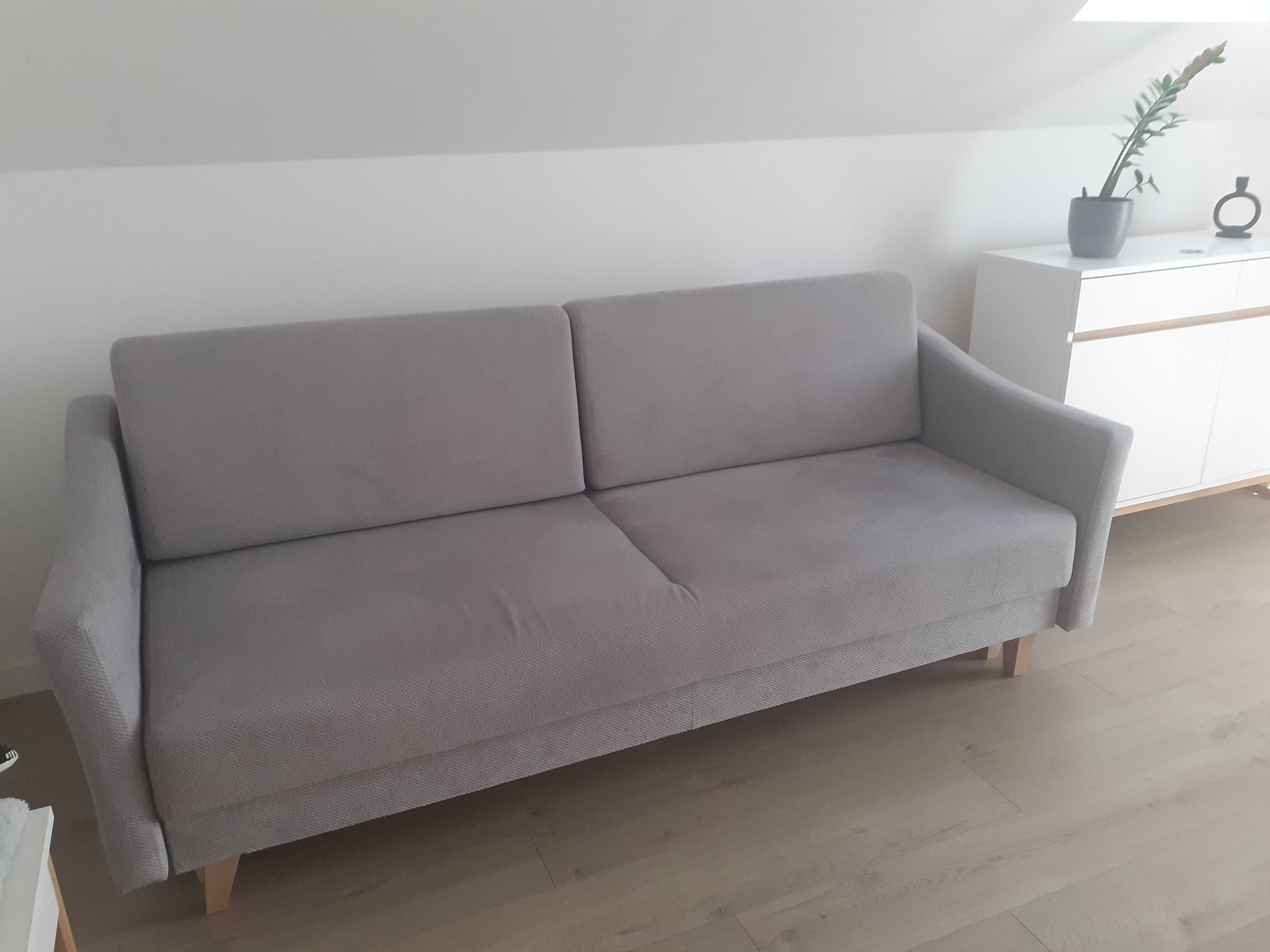 Szara sofa rozkładana z pojemnikiem na pościel