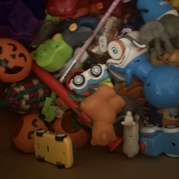 На изображении показана коробка, наполненная разнообразными игрушками.