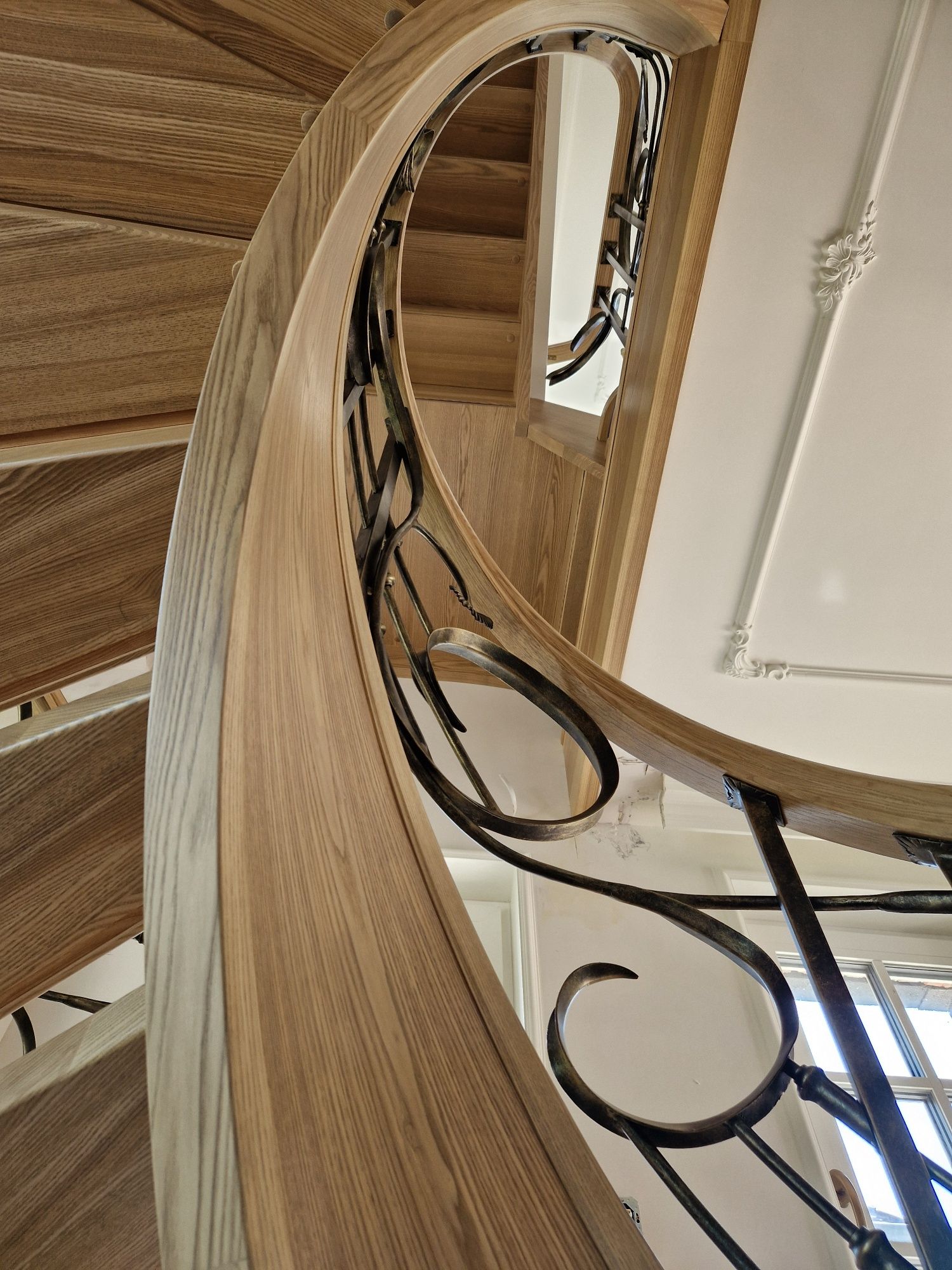 Schody gięte drewniane kręcone kute balustrady