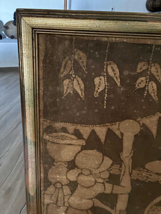 Batique com motivos rurais africanos com moldura em madeira dourada.