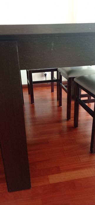 Mesa de madeira castanho escuro com seis cadeiras de pele