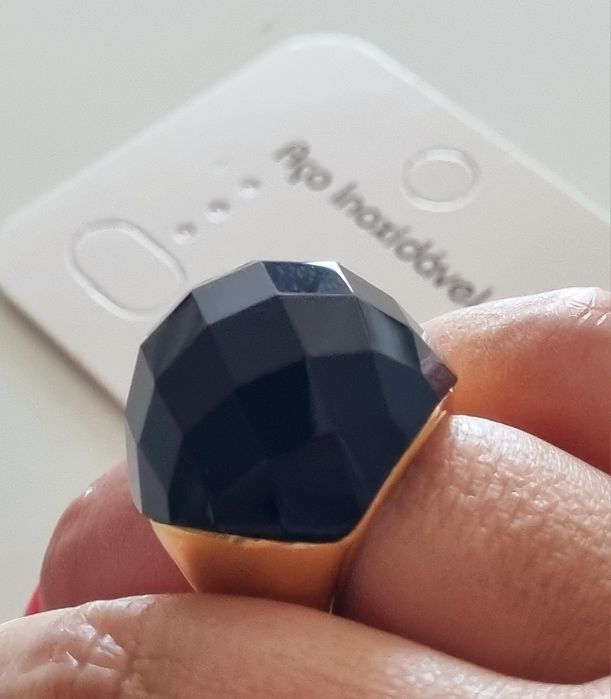 Anel dourado, em aço, com grande pedra preta facetada. T17