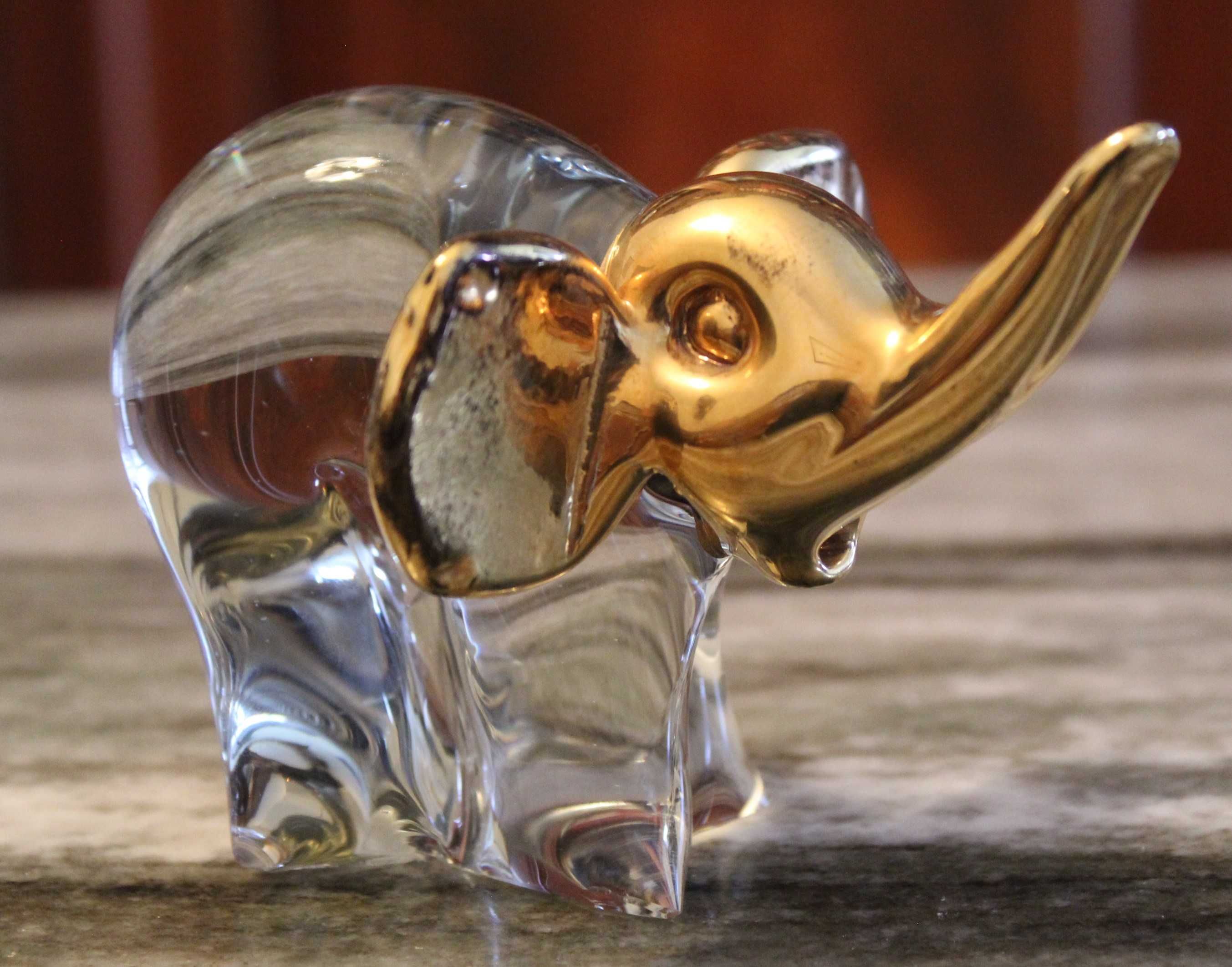 Estatueta de elefante em vidro transparente com detalhes em dourado.