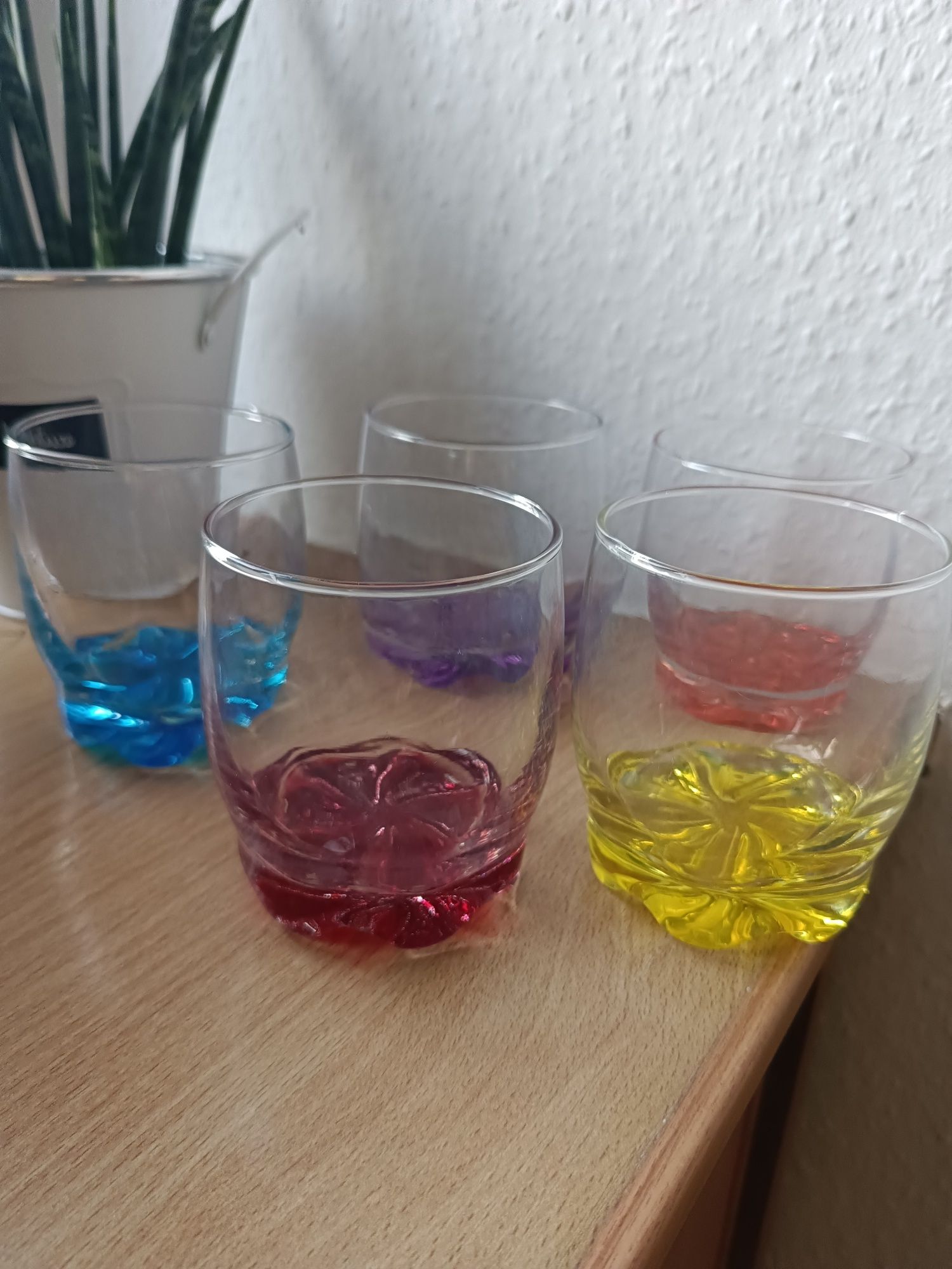 Zestaw szklanek z kolorowymi spodkami.