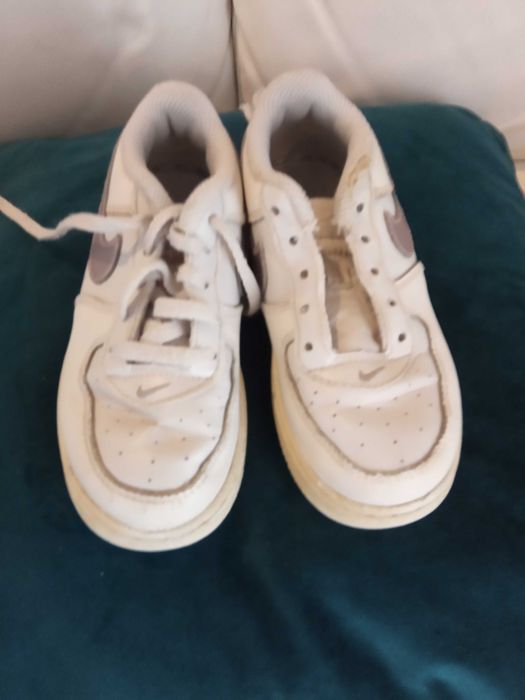 Sapatilhas de criança brancas da marca Nike com algumas marcas de uso.