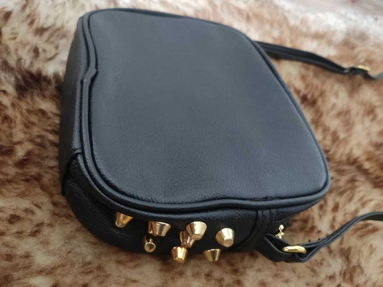 Mała, czarna torebka ze złotymi elementami marki Sinsay.