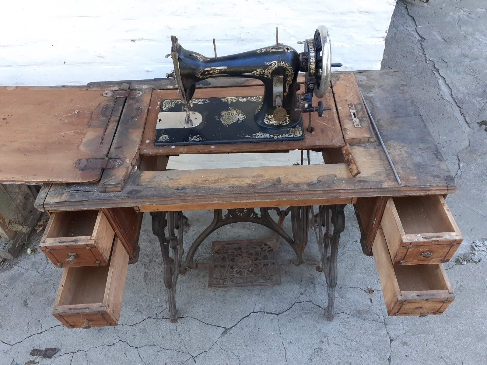 Антикварна швейна машина Зінгер стаціонарна на своїй тумбі.