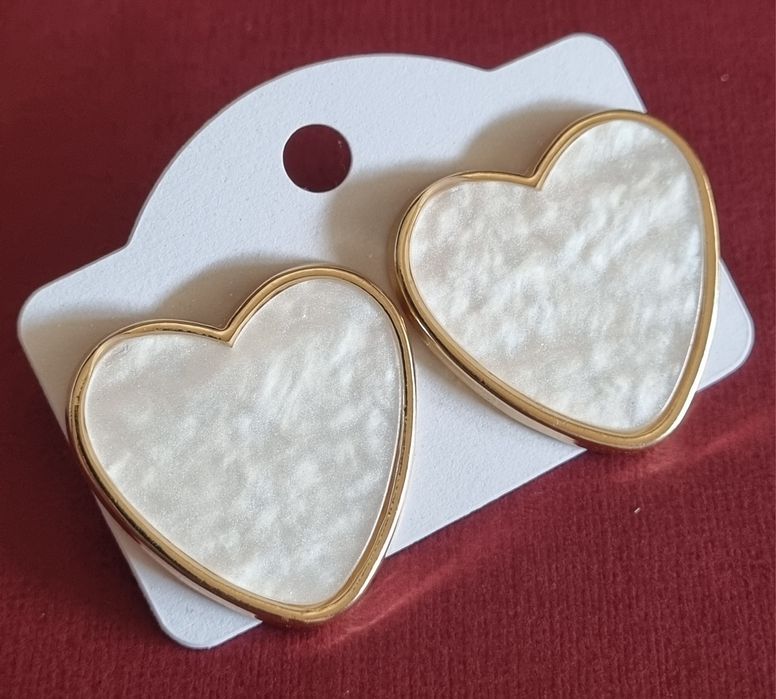 Brincos, de picos, com forma de coração branco delineado a dourado.