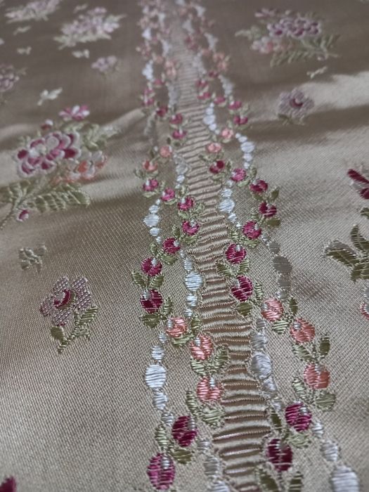 Colcha acetinada antiga com fundo amarelo e bordada com flores.