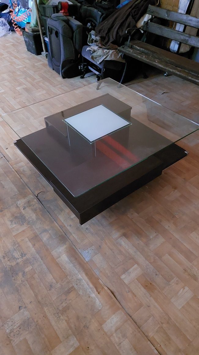 Stolik ze szklanym blatem.
Wymiary: szerokość 100 x100; wysokość 42.
G