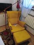 Fotel Ikea standmon z podnóżkiem i czerwoną lampą.