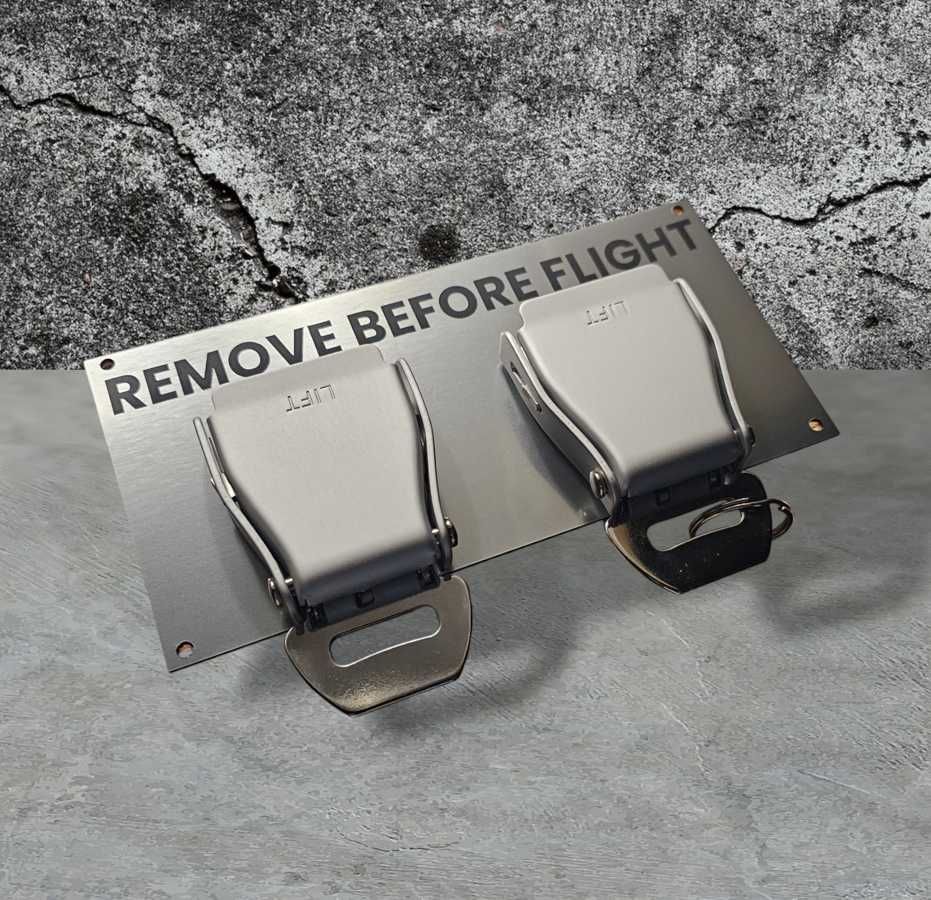 Wieszak na klucze z pasami lotniczymi i napisem REMOVE BEFORE FLIGHT