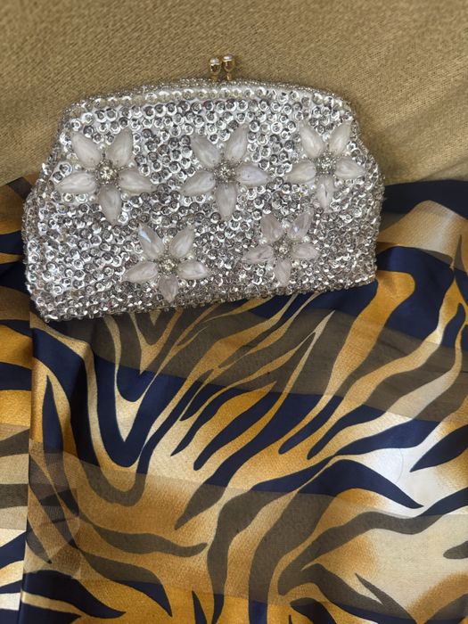 Mala com micangas prateadas e fores compoe o conjunto