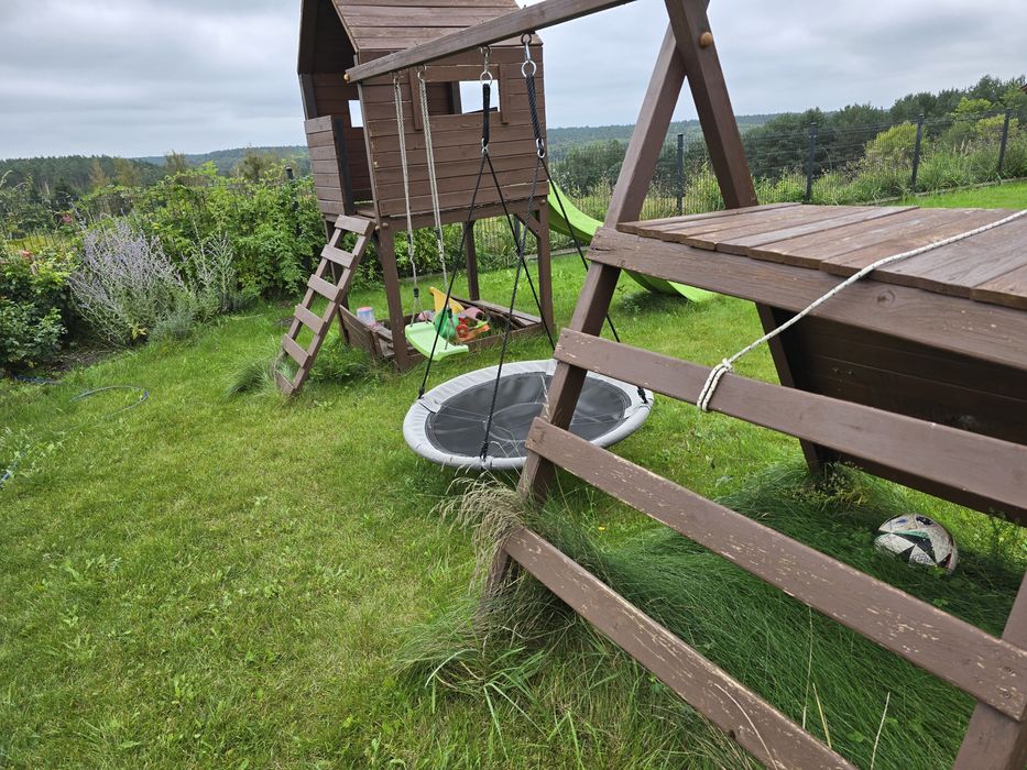 Drewniany plac zabaw z domkiem, zjeżdżalnią, huśtawką i ścianką wspina