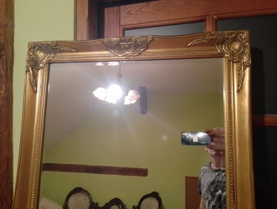 Duże lustro fazowane zdobione prostokątne w złotej ramie.