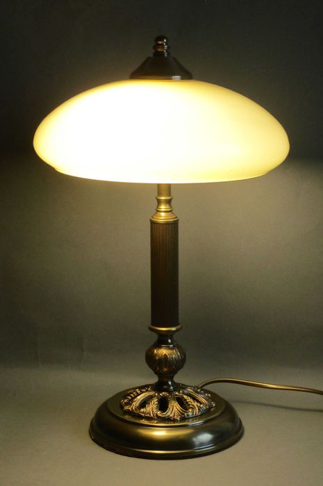 Stara, mosiężna lampka ze zdobioną podstawą.